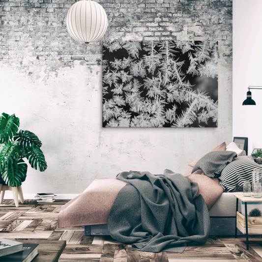 Black-and-white macro view of intricate frost formations spreading across a surface, with delicate, needle-like crystals.