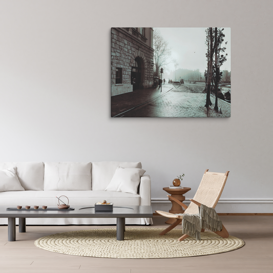 Foggy European plaza with wet cobblestone paving leading past a grand stone building with arched entrance.