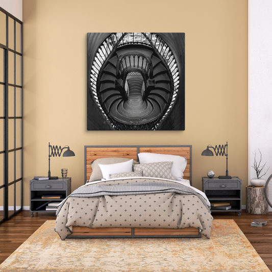 Black-and-white low-angle view looking straight up a grand, ornate spiral staircase.