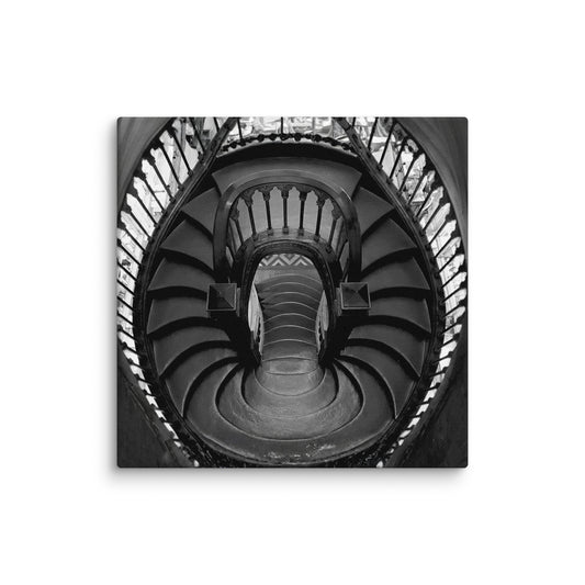 Black-and-white low-angle view looking straight up a grand, ornate spiral staircase.